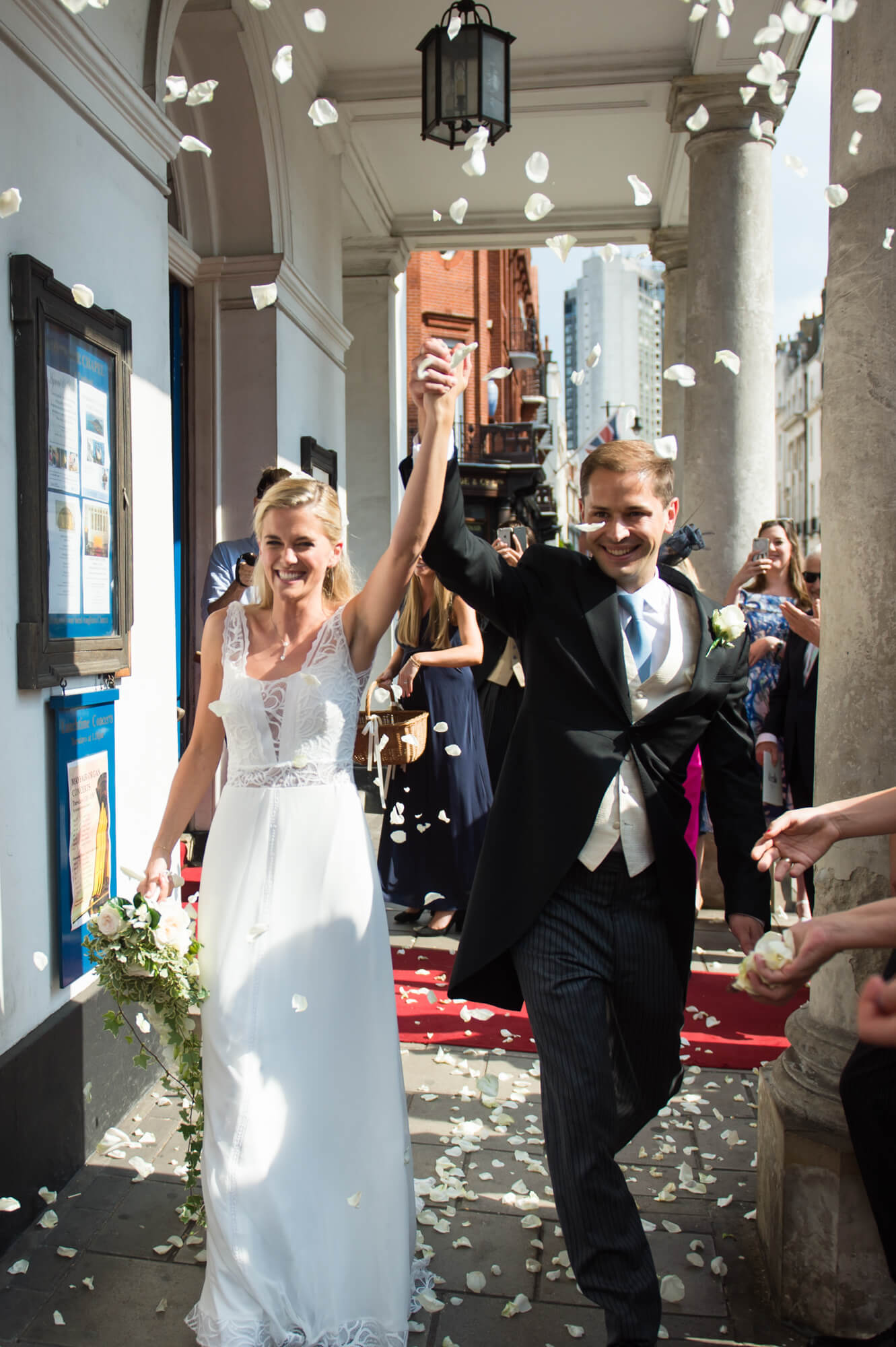 A bride and groom with their hands held high in the air after they have just got married